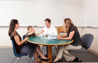 Child with two parents and a teacher sitting around a table